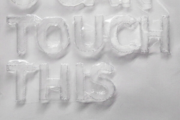 Plakat der Ausstellung der Klasse für Buchkunst zur Jahresausstellung 2026. Eine tiefgezogne, transparente Plastikfolie – zu lesen ist: U Can Touch This