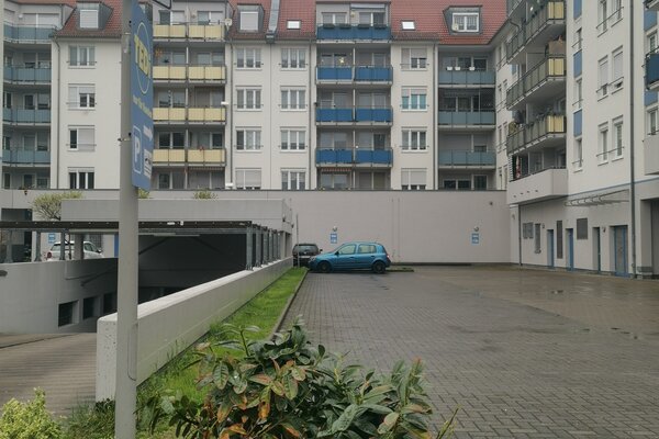 Auf dem Bild ist ein trister gepflasterter Innenhof zwischen mehrstöckigen Häusern zu sehen. Ein Auto ist dort geparkt. Links im Bild ist ein Schild zu erkennen auf dem "Spielen verboten" steht.