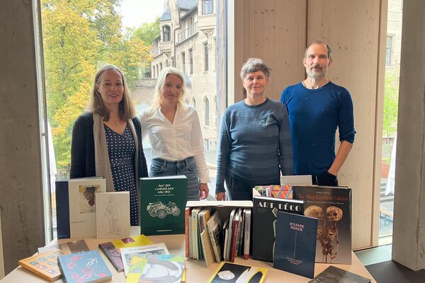 Erste Übergabe von Büchern am 8. Oktober 2025 in der Bibliothek der Burg Giebichenstein Kunsthochschule Halle. V.l.n.r.: Anne-Kathrin Bernsdorf und Katharina Loos (Burg-Bibliothek) sowie Ruth Heftrig und René Schäffer (BBK).